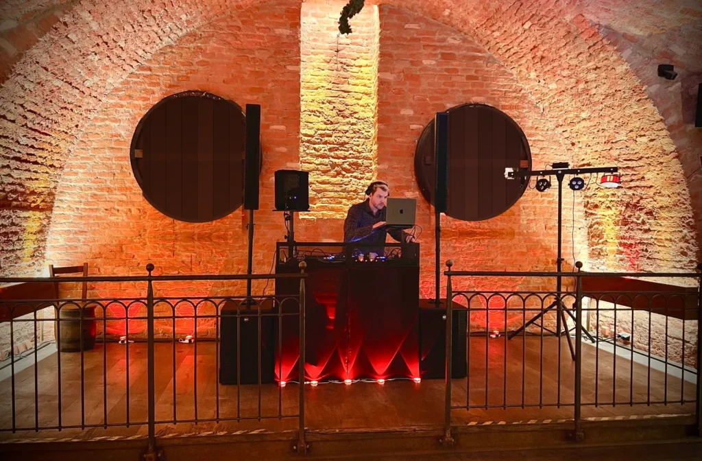 DJ Geburtstag München – DJ New Inside am DJ-Pult mit warmem Licht in einem Gewölbekeller mit großen Bierfässern