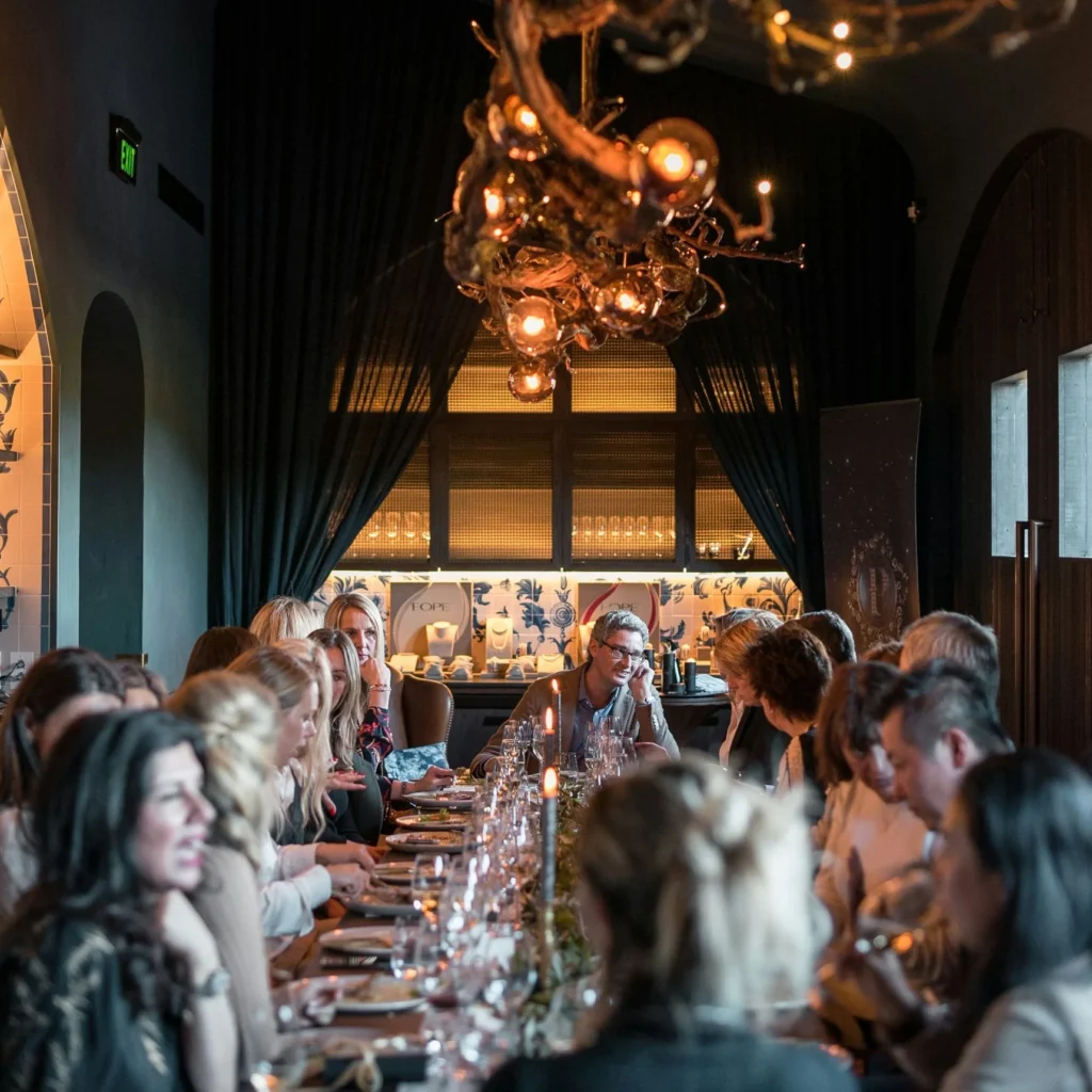 Firmenfeier in München – Gäste beim Dinner an einer langen, festlich gedeckten Tafel mit Kerzenlicht